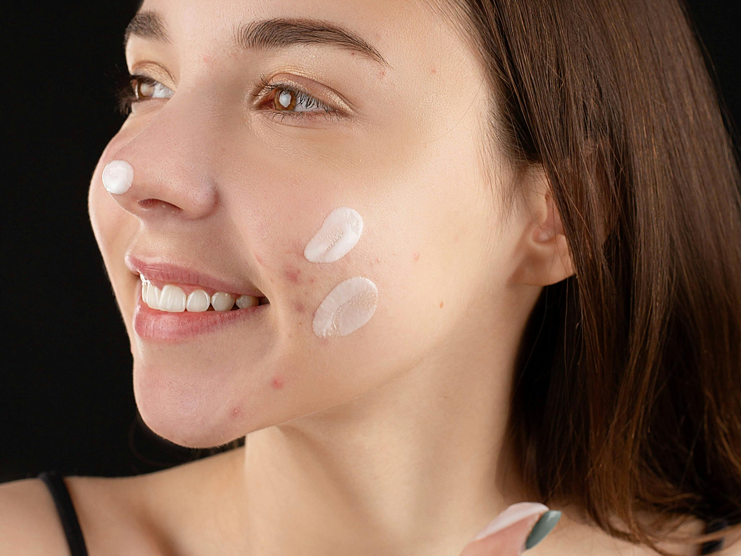 chica joven sonriendo con crema en su rostro.